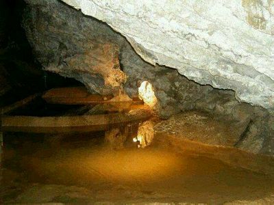 Here we see an underground pool, well lit and showing the golden colour typical of these caves. At the top of the picture, a thick sheet of strongly striated white rock hangs in front of a mass of grey.