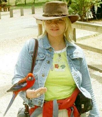 an adult crimson rosella perches on Paula's hand